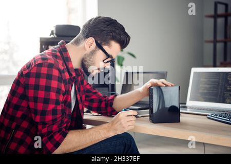 Profile side view portrait of attractive focused experienced guy fixing detail making upgrade at work place station indoors Stock Photo
