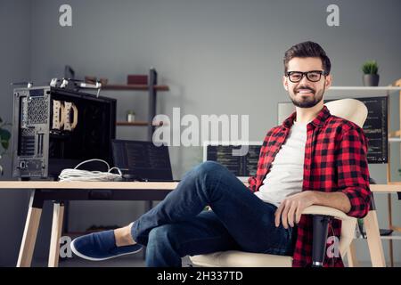 Portrait of attractive smart clever cheerful guy hacker remote support assistance company director at work place station indoors Stock Photo
