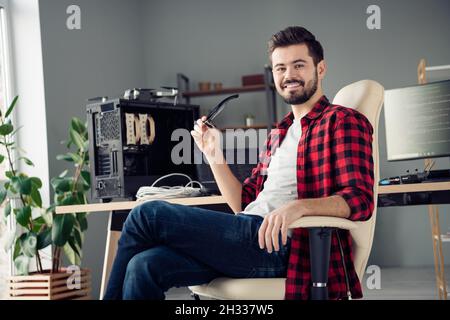Portrait of attractive intellectual cheerful guy hacker top company director leader holding specs at work place station indoors Stock Photo