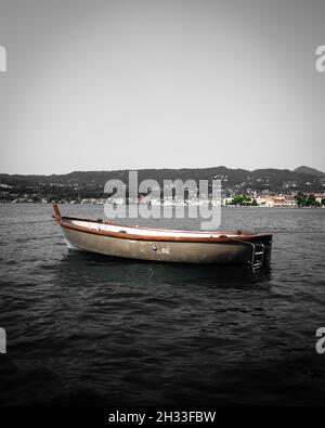 Grayscale vertical shot of an old empty anchored boat on the Lake Garda in Italy Stock Photo