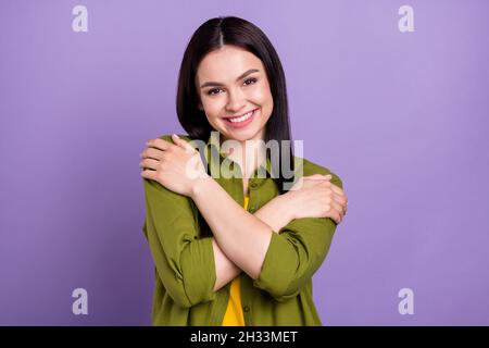 Photo of shiny charming young woman wear khaki outfit hugging herself smiling isolated violet color background Stock Photo