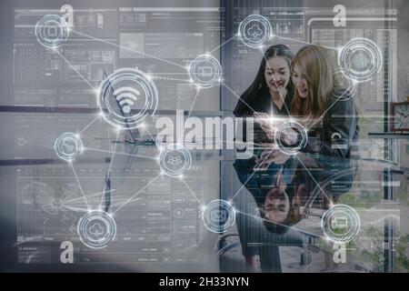 technology digital virtual screen and Wireless communication connecting over the Two Asian young Businesswoman using the technology laptop in the mode Stock Photo