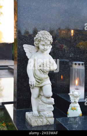 Angel figurine and burning candle on the grave Stock Photo
