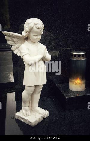 Guardian angel figurine and burning candle on the grave Stock Photo