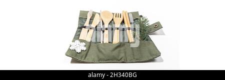 Christmas set of eco friendly cutlery and hygiene products in textile carrying case color khaki with snowflake and fir twig on white. Sustainable life Stock Photo