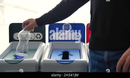 Close-up of man throwing garbage into sorting bins. Media. Man throws garbage into colored bins for sorting. Sorting garbage helps in recycling and Stock Photo