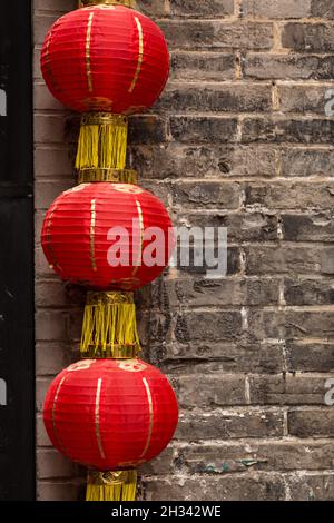 Three red Chinese lanterns hanging on a red brick wall Stock Photo - Alamy