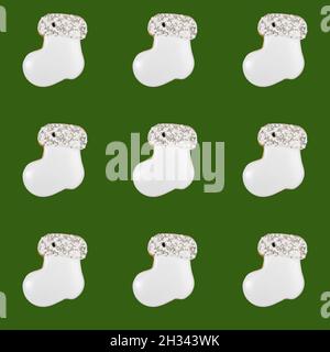 Christmas creative seamless pattern of white glazed and decorated by edible pearls gingerbreads as felt boot or Santa's boot on green background. Xmas Stock Photo