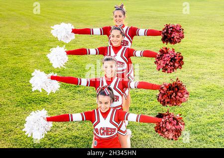 Group of cheerleaders in action with female coach - Concept of unity and team sport - Training at college high school with young happy fit teenagers Stock Photo