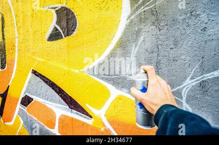 Detail of street artist painting colorful graffiti on public wall - Modern art concept with urban guy drawing live murales with multi color spray Stock Photo