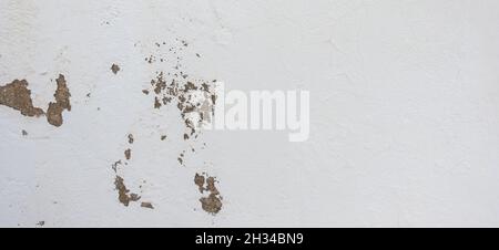 Old cracked weathered shabby white painted plastered peeled wall background. Chipped broken uneven rough stucco wall texture wallpaper Stock Photo