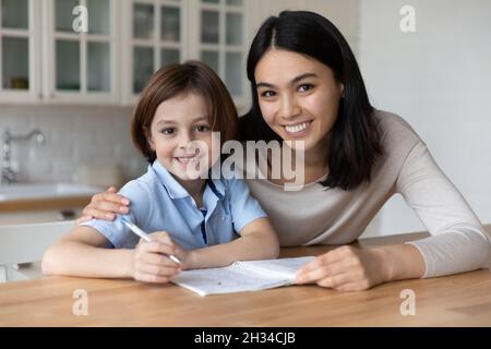 Happy mom and schoolboy son doing school homework Stock Photo