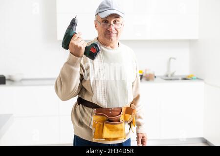 Mature Male Serviceman Repairing With Toolbox In Kitchen Stock Photo