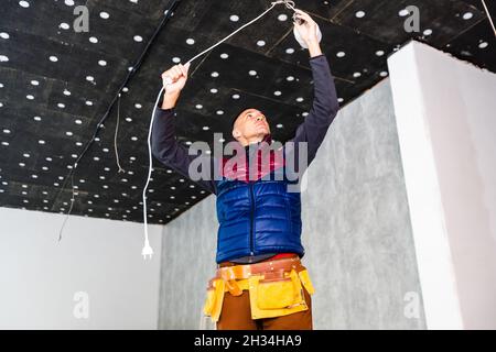 Electrician repairing ceiling light, working Stock Photo