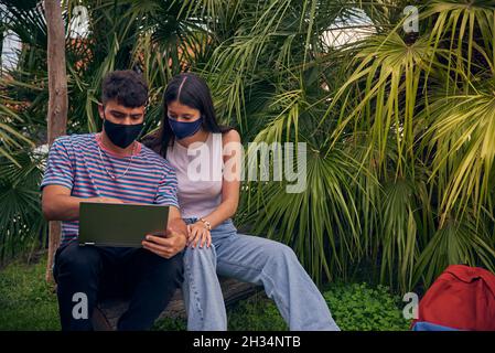 young couple looking a laptop and talking to friends Stock Photo
