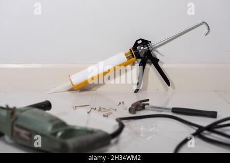 white silicone sealant cartridge and yellow-black sealant gun Stock Photo