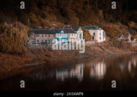 Landscape of cottages and buildings near a lake surrounded by trees and bushes in autumn Stock Photo
