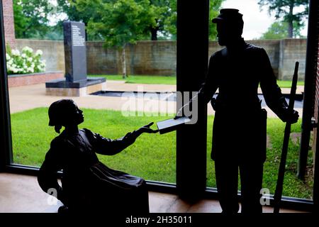 Shilouette of black Union soldier handing book to freed slave girl inside the Corinth Civil War Interpretive Center of Shiloh National Military Park i Stock Photo