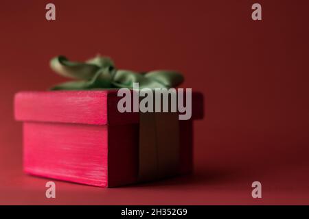 Pink gift box with a green ribbon on a red surface Stock Photo