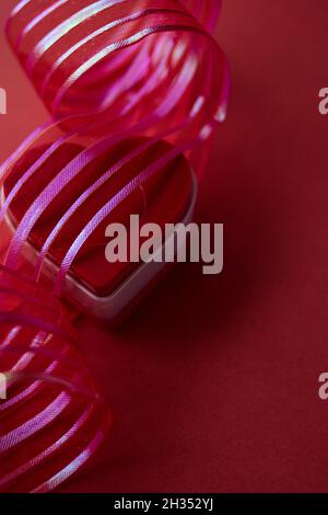 Red heart shaped chest with red ribbon on a red background Stock Photo