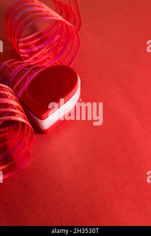 Red heart shaped chest with red ribbon on a red background Stock Photo