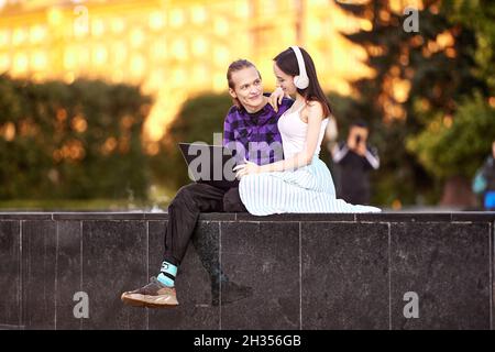 Young couple use laptop for listening to music in park. Stock Photo