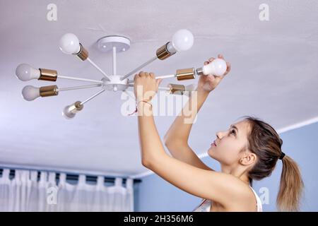 White woman is changing energy-saving LED lamp. Stock Photo