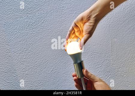 Replacing light bulb in ceiling lamp, Man uses energy saving LED lamps. Stock Photo