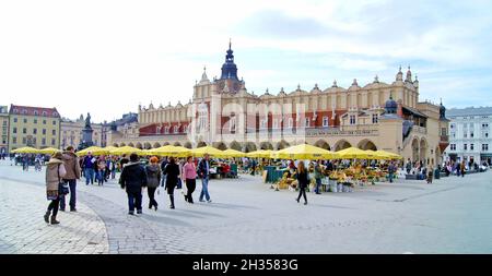 A crowded spring day in the Main Market Square in the Old Town of Krakow, Poland.  The historic square and Cloth Hall are landmarks attesting to their local and world heritage. Stock Photo
