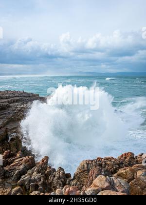 Huge waves crashing onto a rocky shoreline under a brooding sky. Sievers Point (Sieverspunt) Hermanus. Whale Coast. Overberg. Western Cape. South Afri Stock Photo