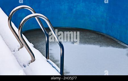 Ice swimming pool in the winter, Steps, hand-rails and garden chair in the frozen blue pool ice-hole Stock Photo