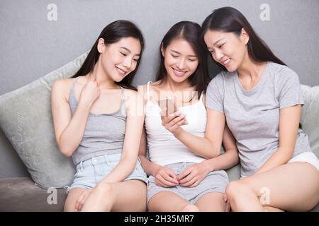 Three best friends using a mobile phone together Stock Photo