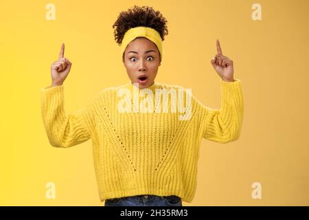 Shocked surprised emotive african-american female student drop jaw widen eyes learn astonishing news pointing raised fingers up gasping concerned Stock Photo