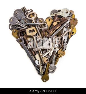 A heart shaped figure isolated on white background laid out from various assorted old multi-colored metal antique keys of different shapes. Home secur Stock Photo