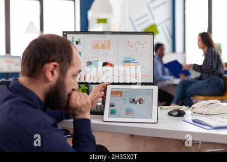 Businessman in wheelchair analyzing digital financial graph using tablet computer working at management statistics in startup company office. Handicapped disabled manager planning marketing strategy Stock Photo