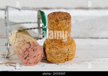 Cork stoppers from a sparkling wine is shown on a surface of a white table, there is a cork of a red wine as well. Stock Photo