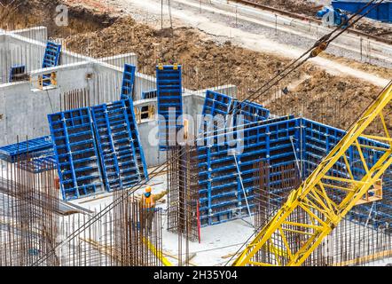 Construction workers install formwork and iron rebars or reinforcing bar for reinforced concrete partitions at the construction site of a large reside Stock Photo