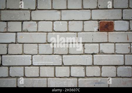 Painted in grey white colors old vintage empty brick wall background with copy space. Rustic cemented house stonewall texture with grunge surface. Shabby Building Facade With Damaged Plaster Stock Photo