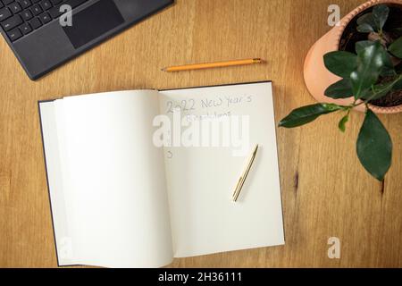 New Year Resolution Goal List 2022 Business office desk with notebook written in handwriting about plan listing of new year goals and resolutions Stock Photo