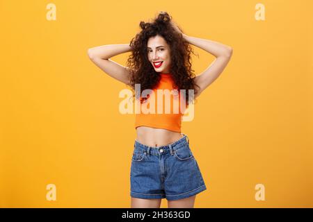 Woman posing for boyfriend being pleased with new look after visiting hairdresser touching curly hairstyle flirty and carefree smiling sensualy Stock Photo