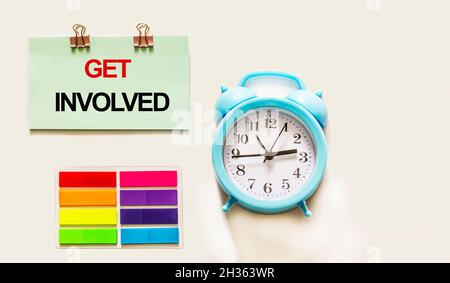 Get involved text written on sticker next to alarm clock on white background. Motivational concept image Stock Photo