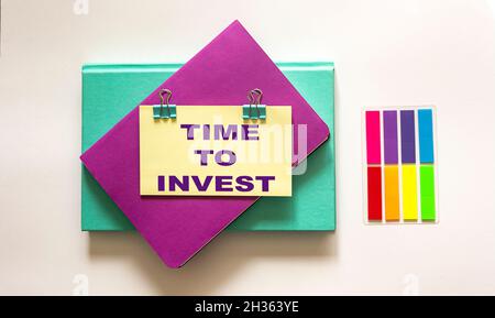 Light card with text Time to Invest on white background with notepads and sticker Stock Photo