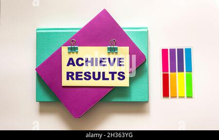 achieve results, text is written on a sticker. Colored notepads lie on a white Stock Photo