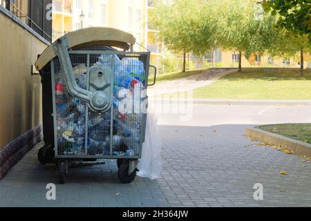 Plastic bottles are collected in a container for sending for recycling. Dumpsters being full with garbage in city. Stock Photo