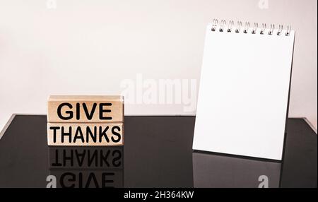 give thanks - text on wooden blocks with reflection on black mirrored background .Notepad for writing Stock Photo
