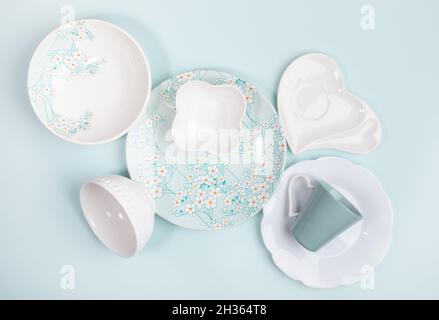 Spring creative festive composition of lot of beautiful tableware white and with floral decor on pastel light blue backdrop. View from above. Flat lay Stock Photo