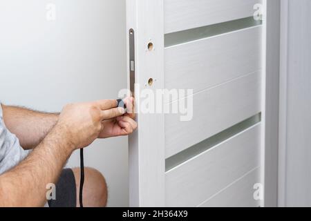 a man fixing a door lock at home using a portable screwdriver Stock Photo