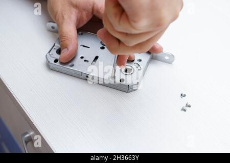 the master disassembles the door lock with a screwdriver to see the cause of the breakdown Stock Photo