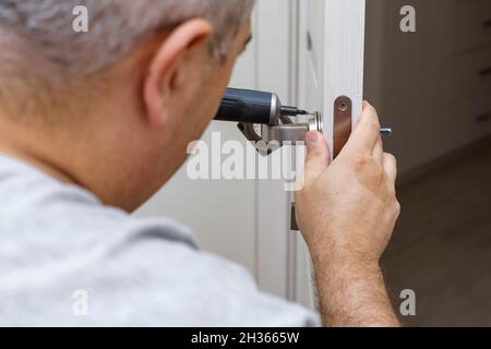 Locksmith repairing or installing a door lock in the house. Stock Photo