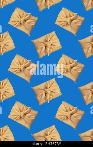Vertical seamless pattern of gift boxes, wrapped in golden fabric in japanese Furoshiki technique on trendy Classic Blue background. Valentine's day, Stock Photo